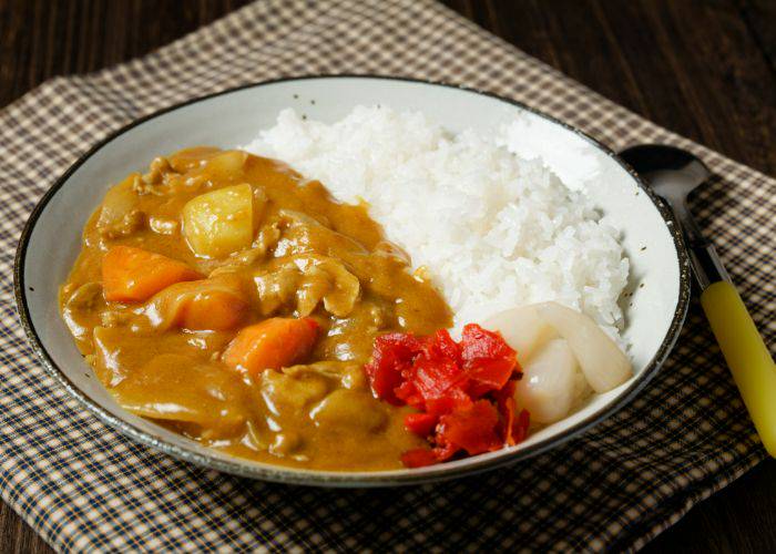 A serving of Japanese curry. The bowl is split down the middle with curry on one side and rice on the other.